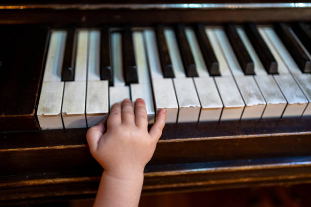 istock Child's hand gently pressing piano keys, exploring music indoors 2191347799