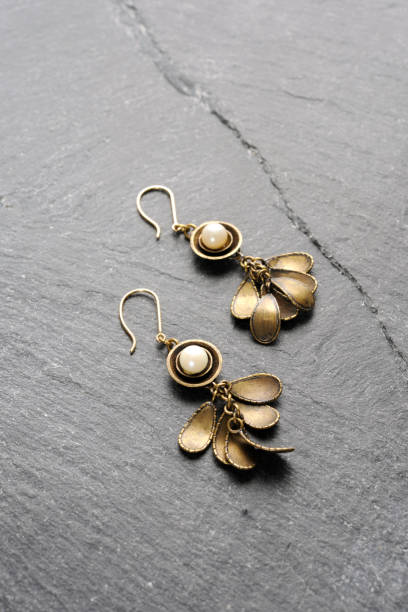 Brass earrings with pearl on a black slate with copy space.