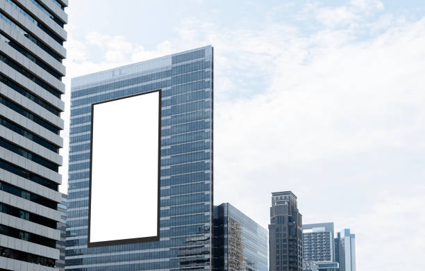 istock Mock up white vertical large LED display billboard on tower building with blue sky background .Clipping path for mockup 2191354460