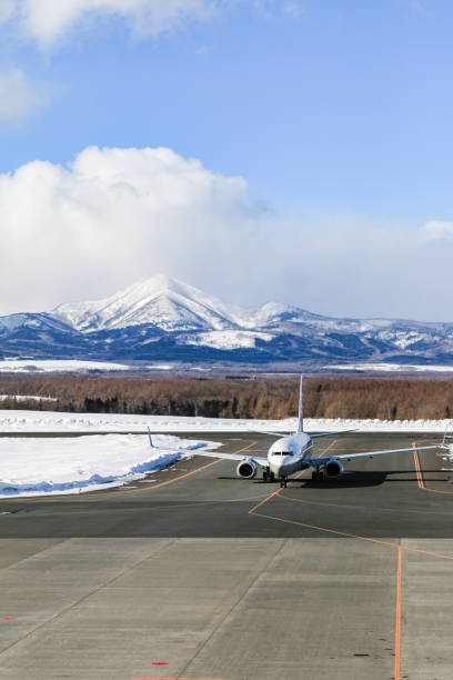 istock Airplane on Runway with Snow Capped Mountain Backdrop, Hokkaido, Japan 2191357533