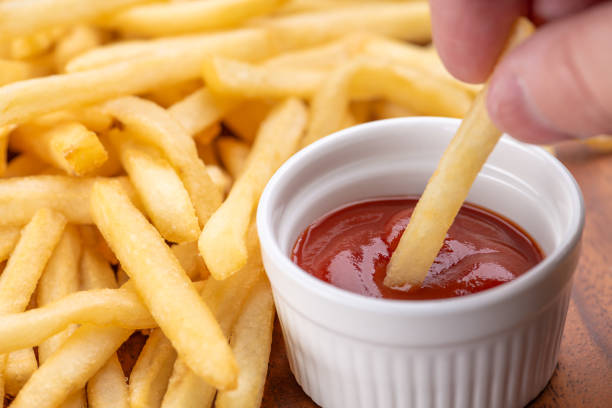 Dipping Fried Potatoes in Ketchup and Eating