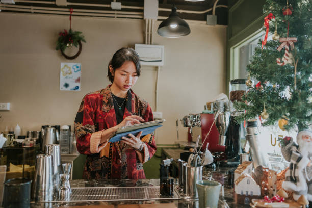 Barista is reading online coffee and beverage ordering, Christmas theme Attire Using a Digital Tablet in a Cozy Café During the Holiday Season