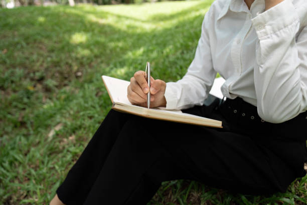 istock Person Reading and Working Outdoors in a Relaxed Natural Setting with Notebook and Pen 2191359516