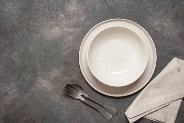 istock Two empty plates with cutlery and linen napkin on dark rustic background, top view, minimal table setting 2191369173