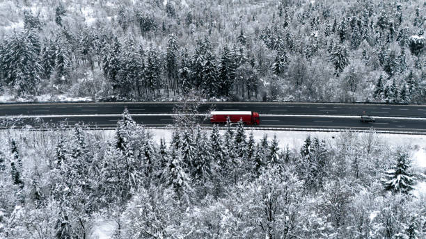 istock Red Truck Driving Through Snow-Covered Forest on a Winter Highway 2191371987
