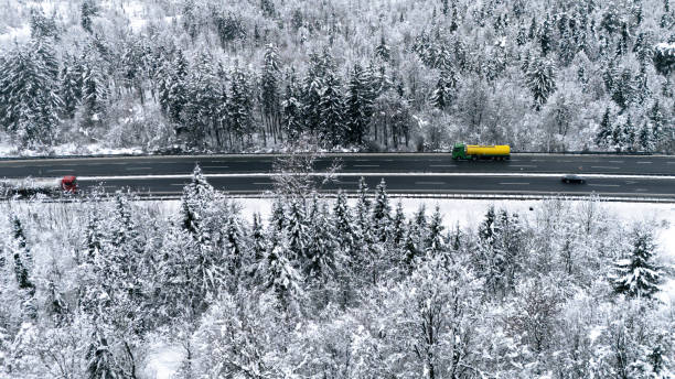 istock Snowy Highway with Colorful Trucks and Winter Forest 2191371998