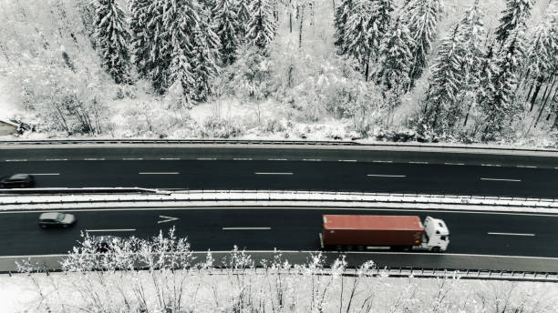 istock Truck Driving on Snowy Highway Through Winter Forest 2191372179