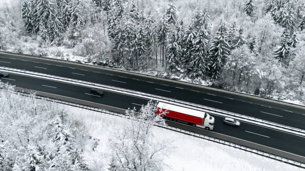 istock Red Cargo Truck Driving on Snowy Highway Through Winter Forest 2191372202