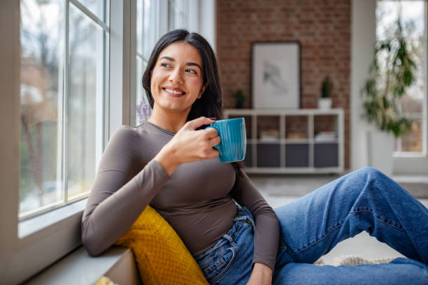 istock Happy woman with coffee looking outside in cozy space 2191373418