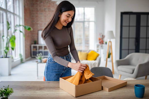 istock Woman removing orange fabric from an open box excitedly. 2191374528