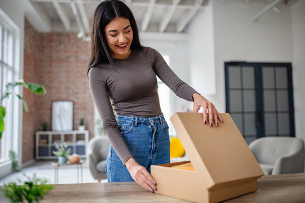 istock Woman happily opening box in modern living space. 2191374546