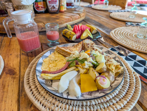 Colorful and healthy breakfast plate with scrambled eggs, vegetables, pancakes, fruits, and juice is served on a wooden table in tanzania, offering a delightful start to the day