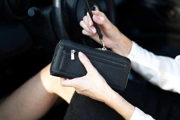istock Woman holding black leather wallet in car. 2191377576