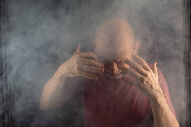 istock Bald and bearded man making expressions with his head down in a studio with a smoky black background. 2191378705