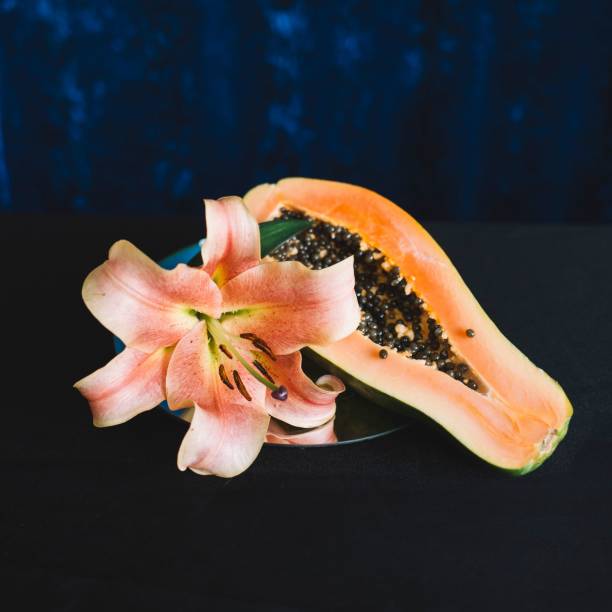 Fresh ripe cut half papaya fruits with seeds on wooden table, flat lay, Varieties of tropical fruit
