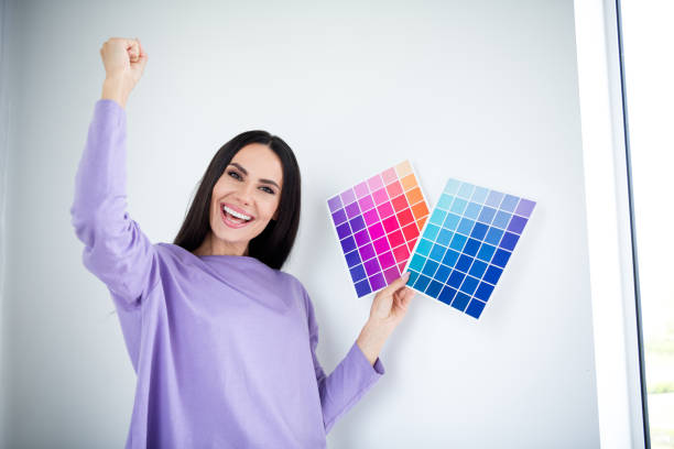 istock Young woman happily holding color samples in trendy pullover during daylight indoors 2191390127