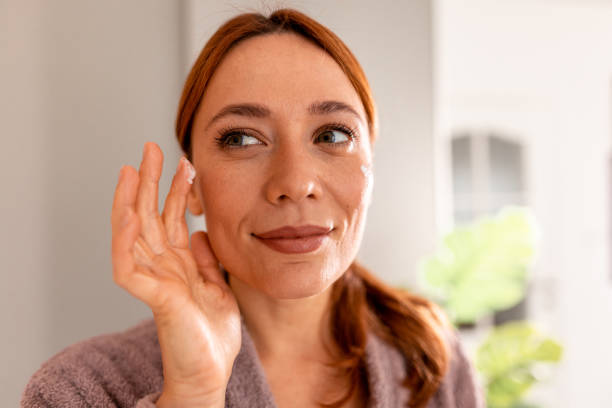 istock Woman applying face cream looking in the mirror 2191394916