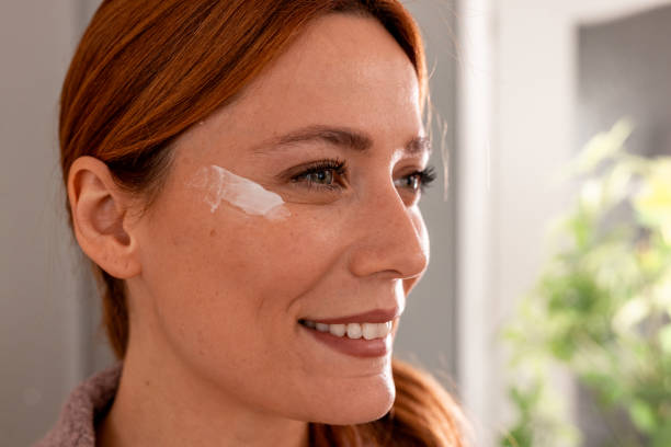 istock Smiling woman applying moisturizing cream on her face 2191395003