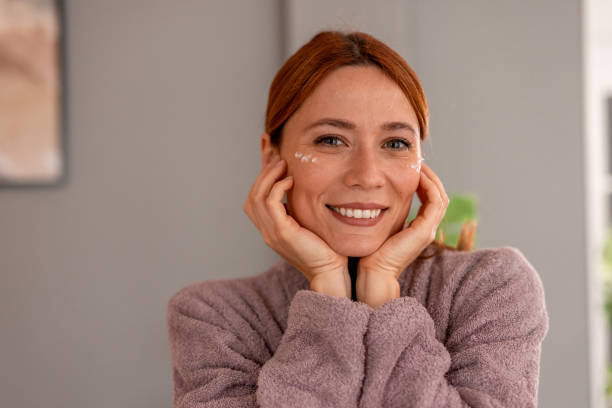 istock Smiling woman applying anti-aging cream on her face 2191395034