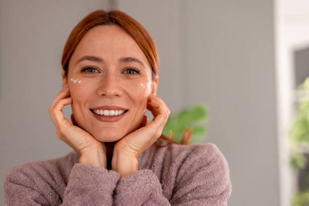 istock Smiling woman applying anti-aging cream on her face 2191395040