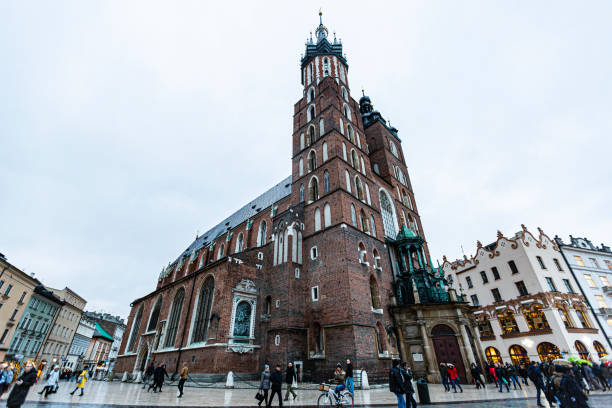 Krakow, Poland - December 5, 2018: St. Mary’s Basilica, with its soaring twin towers and intricate brickwork, commands attention in Krakow’s Main Market Square. A masterpiece of Gothic architecture, it houses the world-famous Veit Stoss altarpiece and stands as a symbol of the city’s spiritual and cultural heritage.