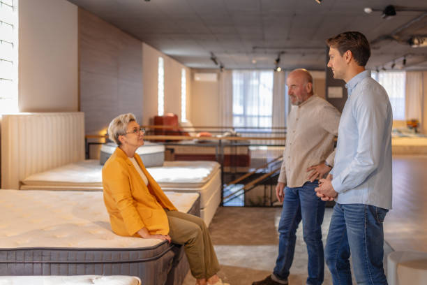 istock Woman sitting on mattress while men advise in store. 2191395415