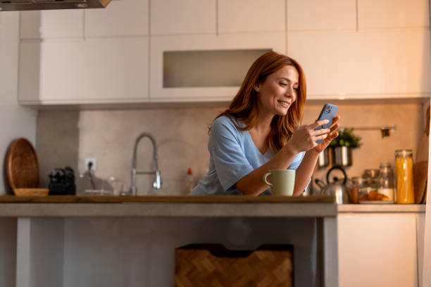 istock Woman Relaxing in Modern Kitchen Using Smartphone and Drinking Tea 2191395506