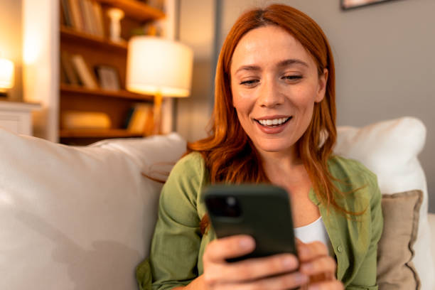 istock Happy redhead woman using smartphone at home sitting on couch 2191395675