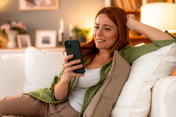 istock Woman relaxing on sofa using smartphone at home 2191395677