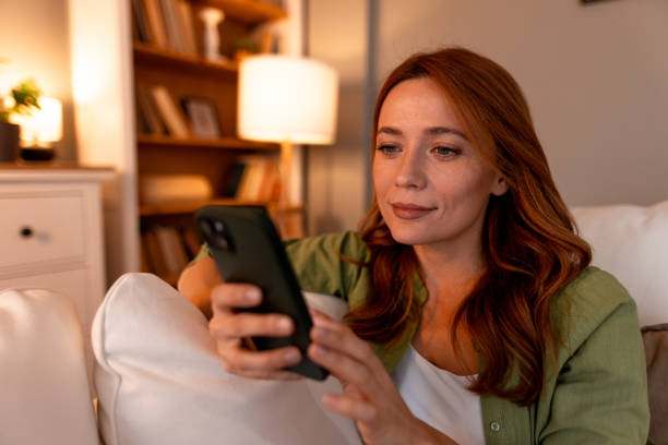 istock Young woman using mobile phone while relaxing on sofa at home 2191395700
