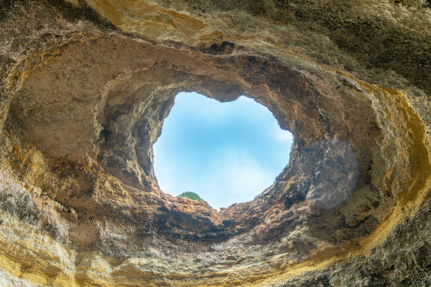 A heart-shaped skylight illuminates the interior of Benagil Cave, one of the most stunning sea caves in the world. Algarve, Portugal.