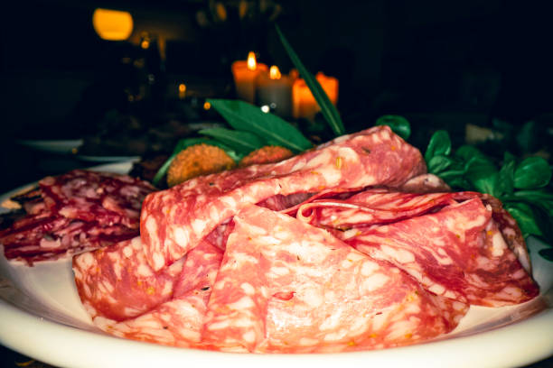 Cold cuts, salami selection close up, on illuminated table at night.