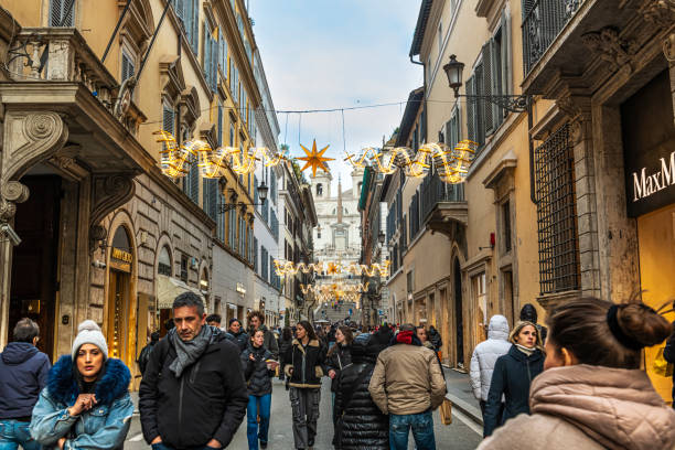 Rome, Italy-December 23, 2024: Via dei Condotti, Christmas decoration along the street and people walking down the street for shopping. On the background, Trinità dei Monti square and the Spanish steps.