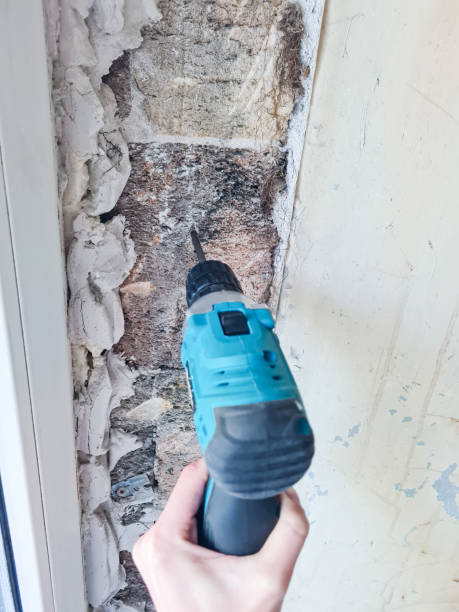istock A person uses an electric drill to drill a hole in a brick wall. 2191399919