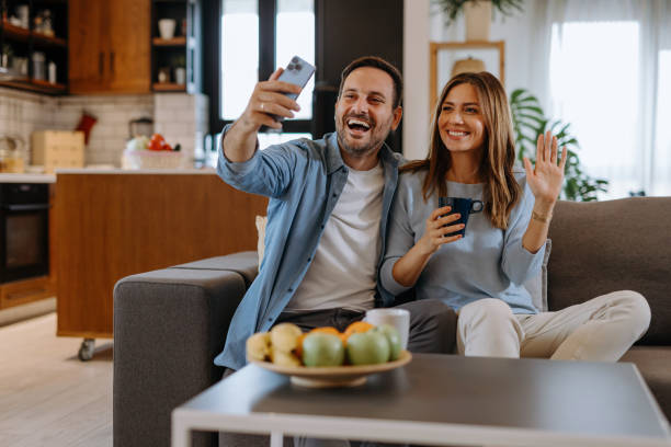 istock Happy couple video calling with family using smartphone at home 2191402255