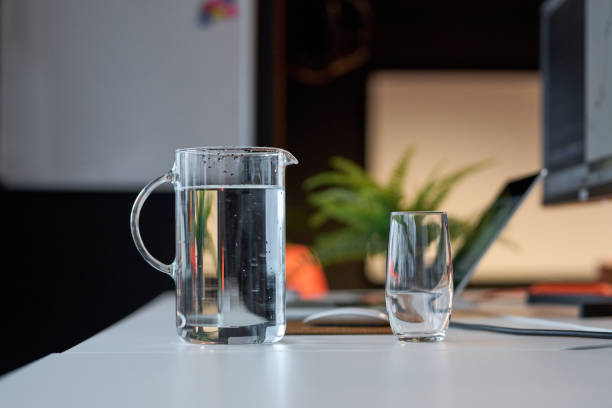 Glass and pitcher of fresh water standing on an office desk promoting hydration and wellbeing in the workplace