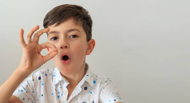 A young boy, aged 6-8, practicing speech therapy exercises. The photo highlights themes of speech correction, developmental support, and language learning. Copy space