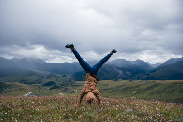 Woman hiker doing a handstand on high altitude mountain meadow