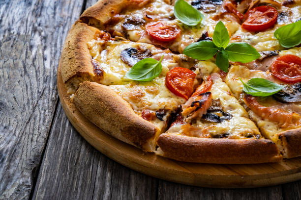 istock Circle vegetarian pizza with mozzarella cheese, mushrooms and tomatoes on wooden table 2191407344