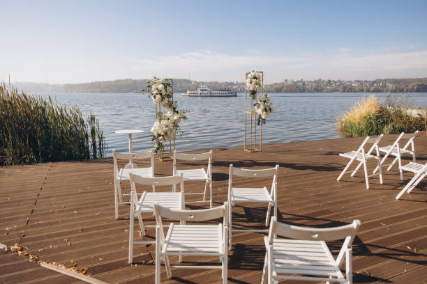istock Wedding ceremony setup with white chairs on a wooden pier overlooking a lake 2191407551