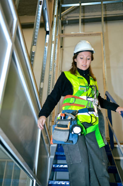 istock Female construction worker carrying plasterboard on metal staircase 2191407638