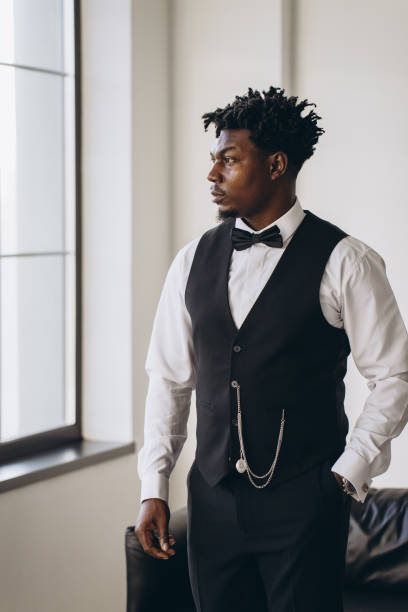 istock Elegant groom getting ready, wearing suit and bow tie, looking out the window 2191407809