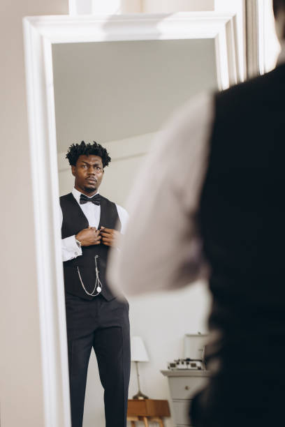 istock Elegant groom adjusting waistcoat in front of mirror getting ready for wedding 2191407885