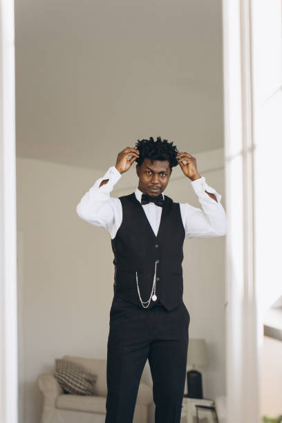 istock Elegant groom adjusting his hair while getting ready for wedding 2191407918