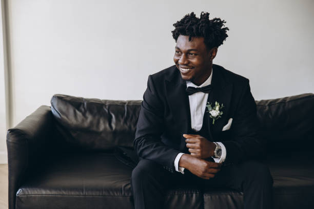 istock Elegant groom smiling and sitting on black sofa waiting for bride 2191408475