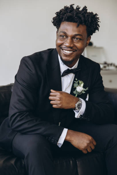 Elegant groom smiling and sitting on sofa