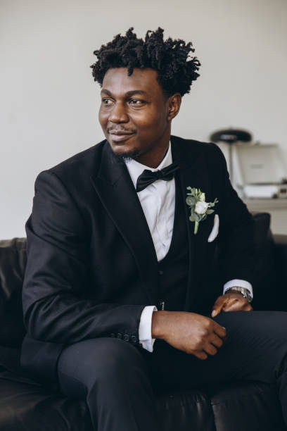 istock Elegant groom wearing black suit sitting on couch waiting for bride 2191408511