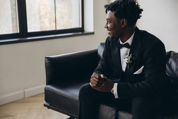 istock Elegant groom sitting on a couch waiting for his bride 2191408519