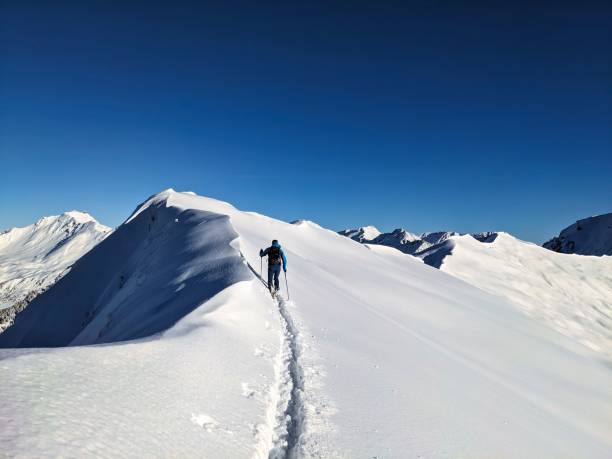 istock A solo hiker is making their ascent up a stunning snowcapped mountain located under a clear blue sky 2191408703