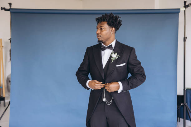 istock Groom wearing elegant suit adjusting jacket in photo studio with blue background 2191408710